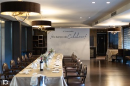 Mesa lista para la comida con photocall al fondo durante fotograf&iacute;a corporativa en eventos.