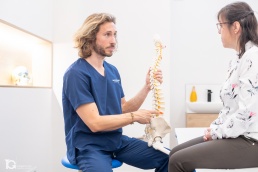 Iñaki Malo explicando la columna vertebral a una paciente en el Centro Samai durante un reportaje de fotografía corporativa en Pamplona