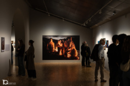 Visitantes observando fotografías en la exposición World Press Photo Barcelona, con Night Crossing de John Moore al centro.