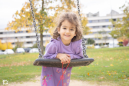 Fotografía familiar en Sarriguren de Ángela jugando en el columpio del parque infantil.