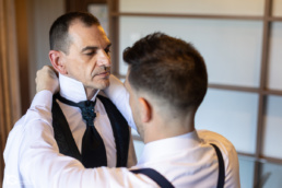 Gonzaga ajustando la corbata de Laro en los preparativos de su boda en el Hotel Tres Reyes de Pamplona.
