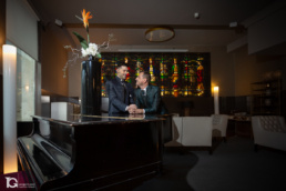 Laro y Gonzaga sonriendo junto al piano en la entrada del hotel.