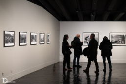 Grupo de personas observando fotograf&iacute;as en una exposici&oacute;n cultural